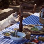 Gatto curioso che osserva un piatto di olive su un tavolo.