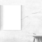 Quadro inclinato su una parete, con strumenti per il fissaggio accanto.