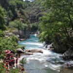 Gruppo di persone in canoa mentre fanno rafting in un fiume italiano circondato da natura.