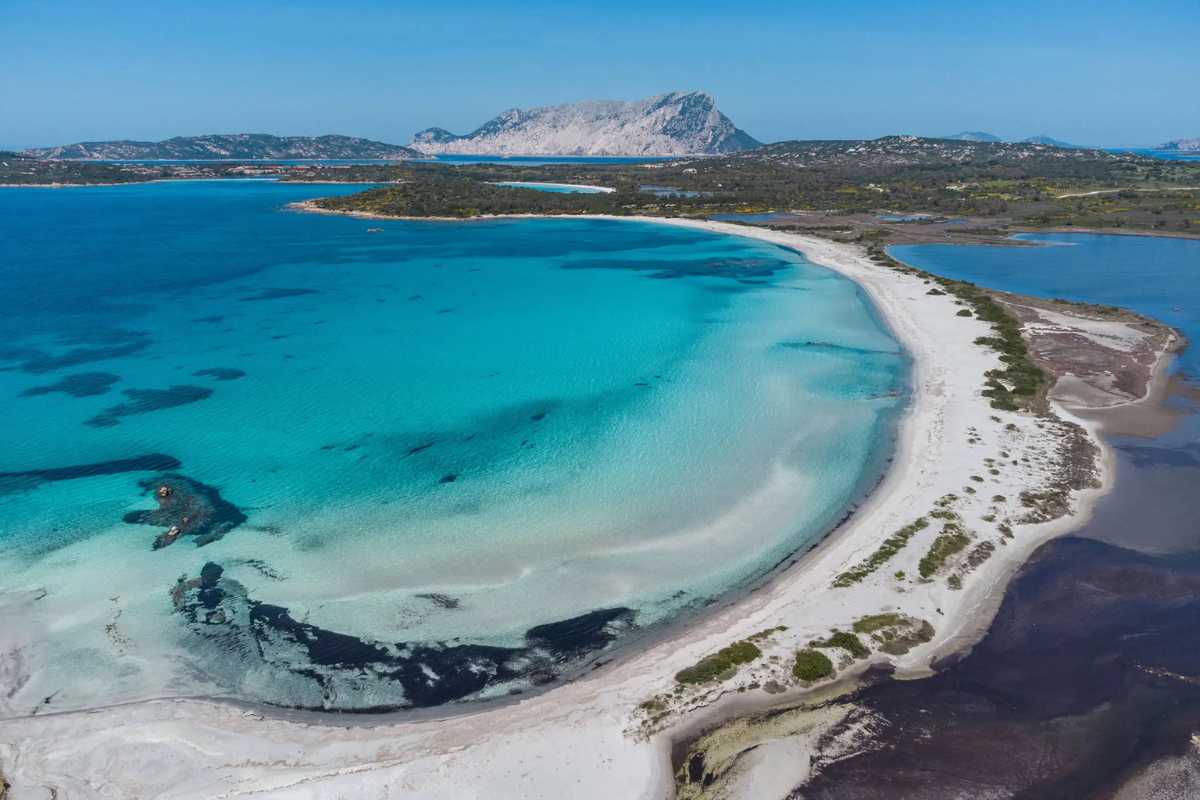 Scorcio di una spiaggia segreta in Sardegna, con sabbia bianca e acque cristalline.